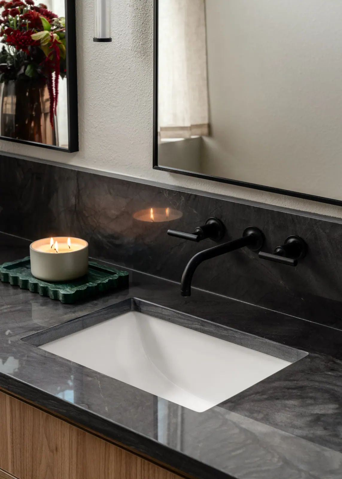 Undermount sink in dark stone with a wall-mounted faucet