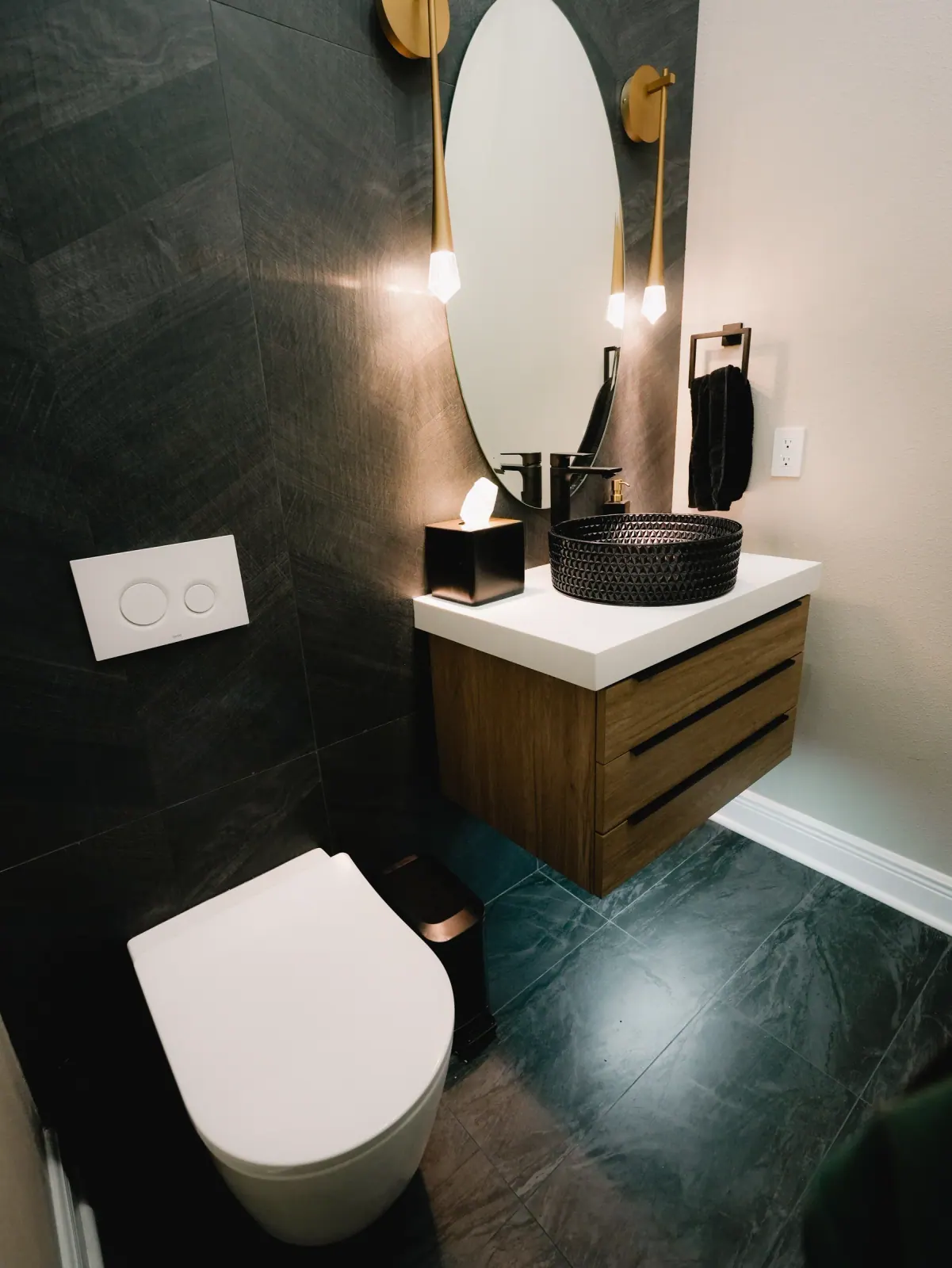 Floating walnut vanity with a vessel sink and dark tile