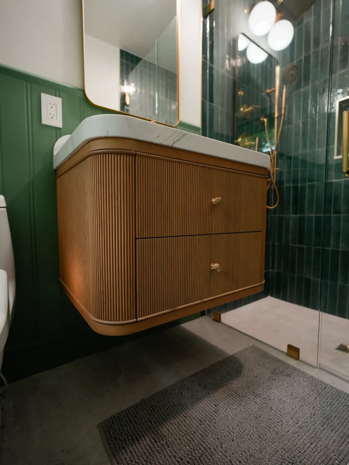 Curved fluted wood vanity against green tile