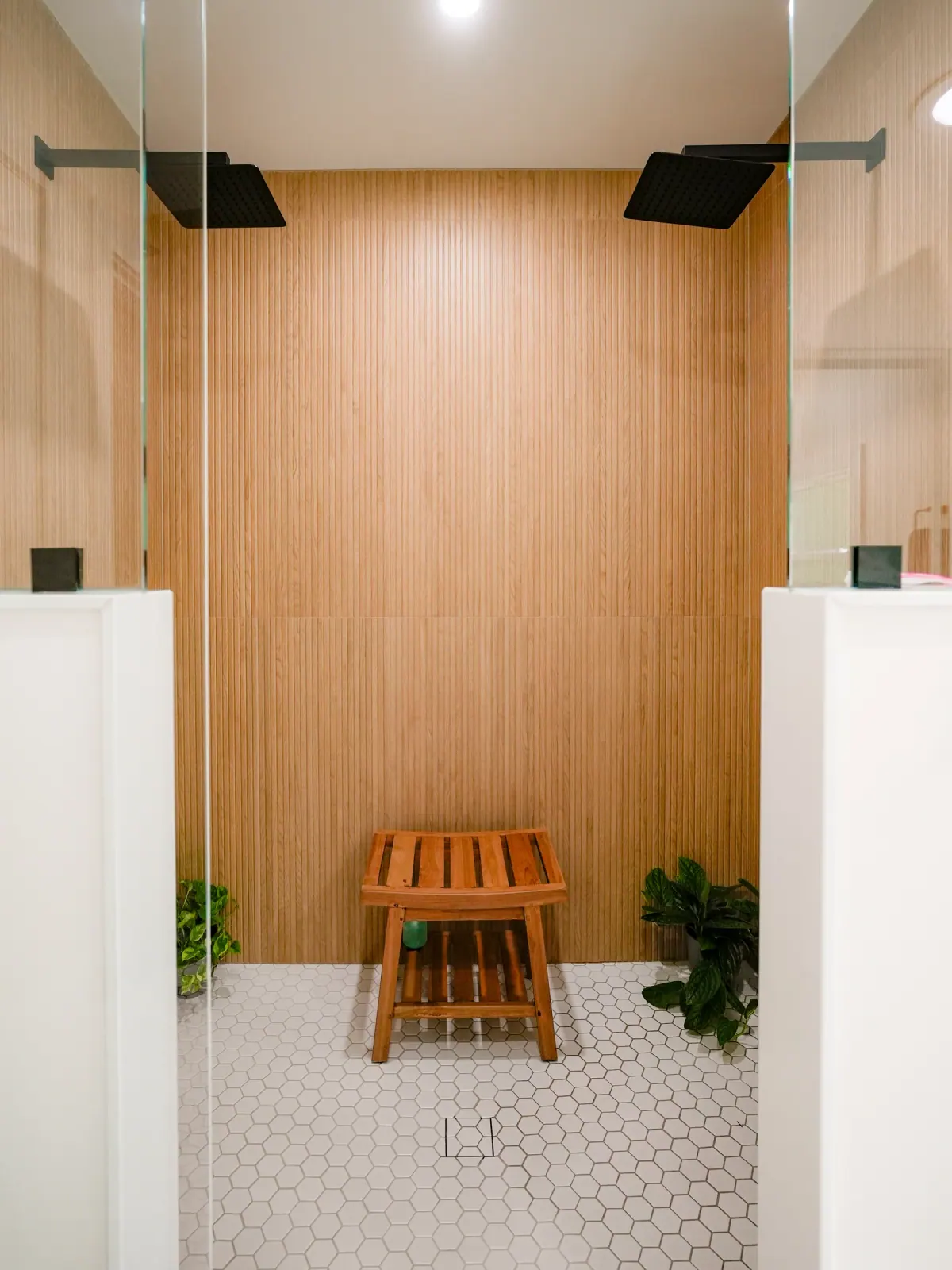 Walk-in shower with warm wood-look slat walls and a teak bench