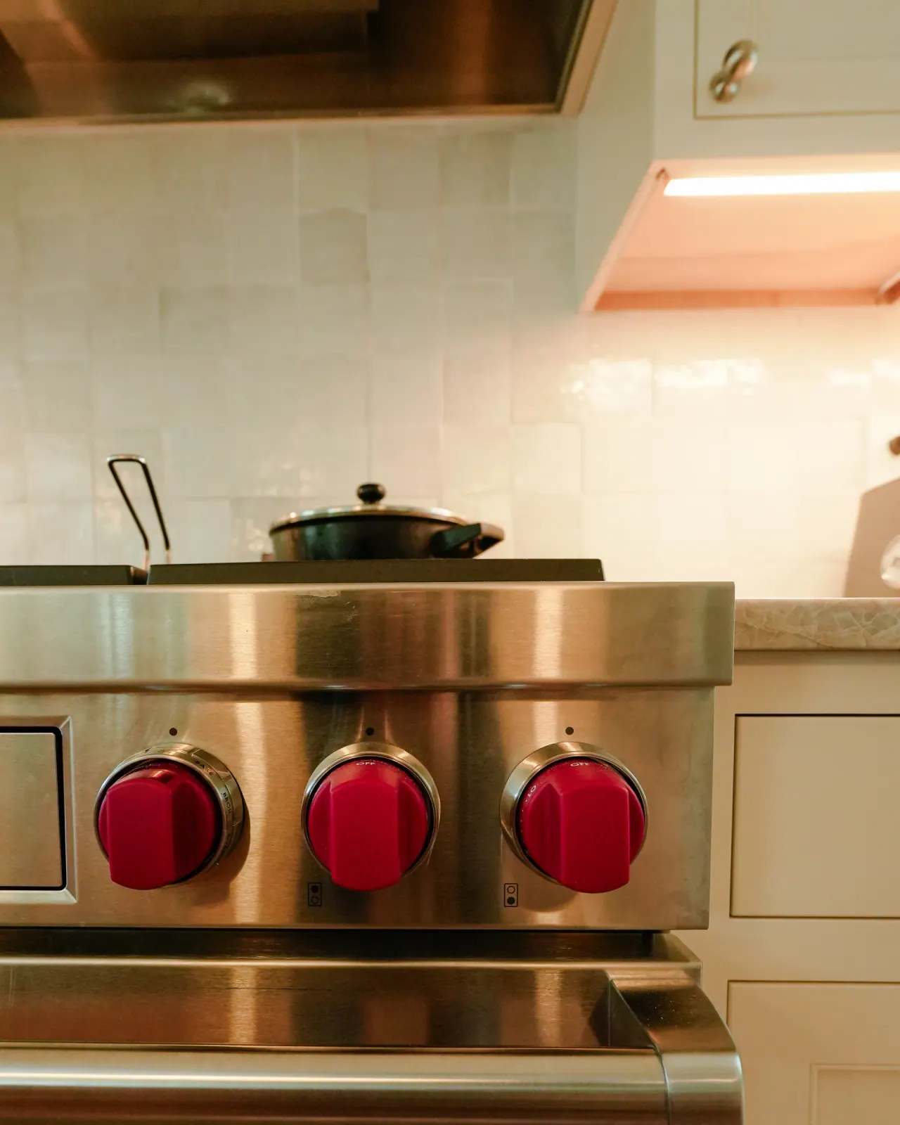 Professional range with red knobs set into white cabinetry
