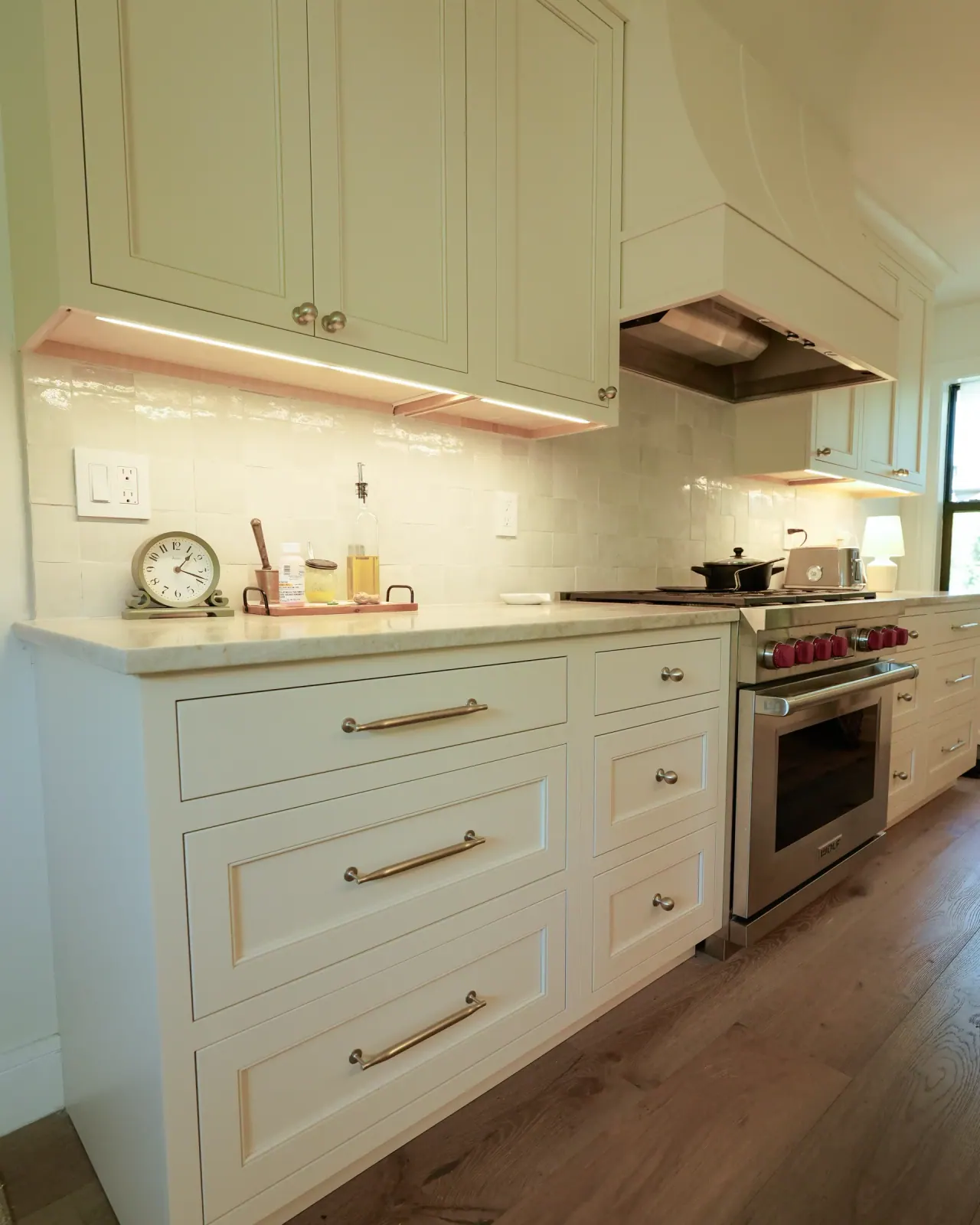White perimeter cabinets with under-cabinet lighting and a pro range